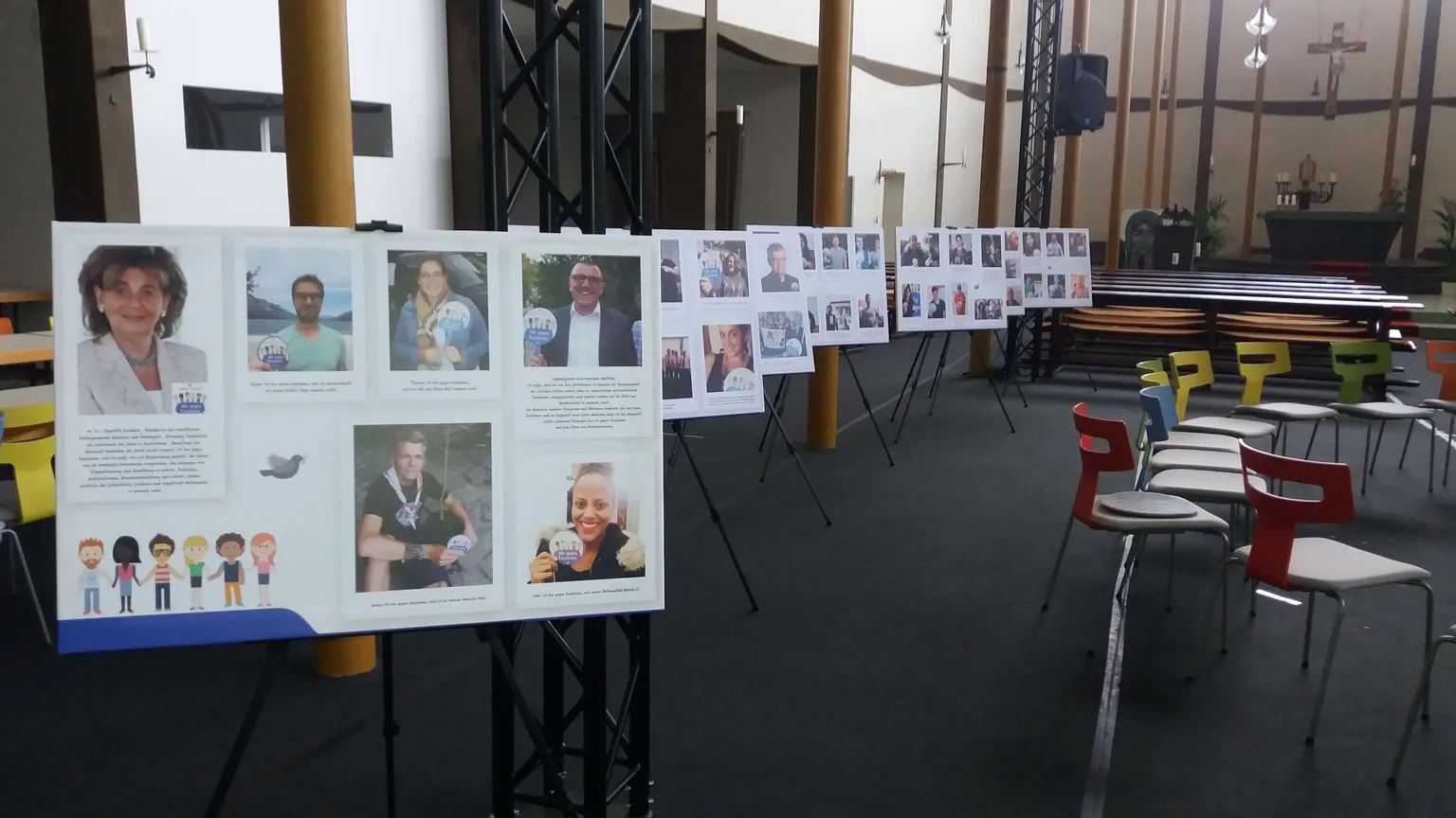The “Wir gegen Rassismus” exhibition: a row of display boards with portraits and quotations, set up in the side aisle of a church
